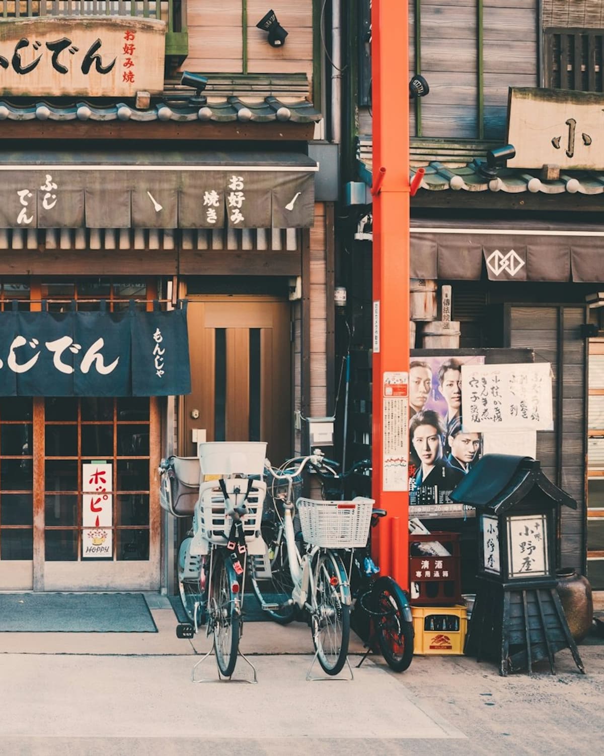 A low-rise okonomiyaki shopfront with noren curtains and bicycles outside