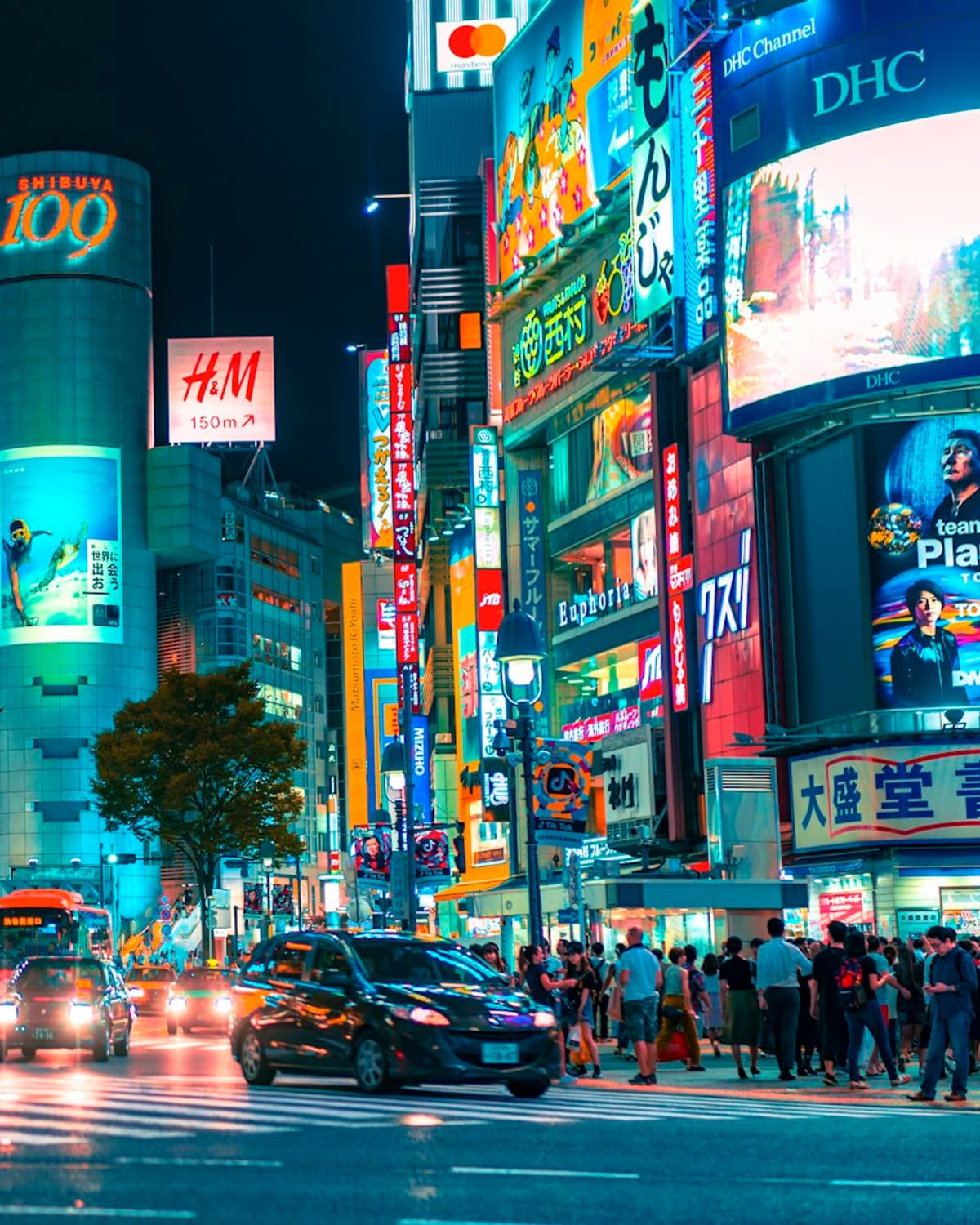 Traffic and illuminated screens around the Shibuya 109 building at night
