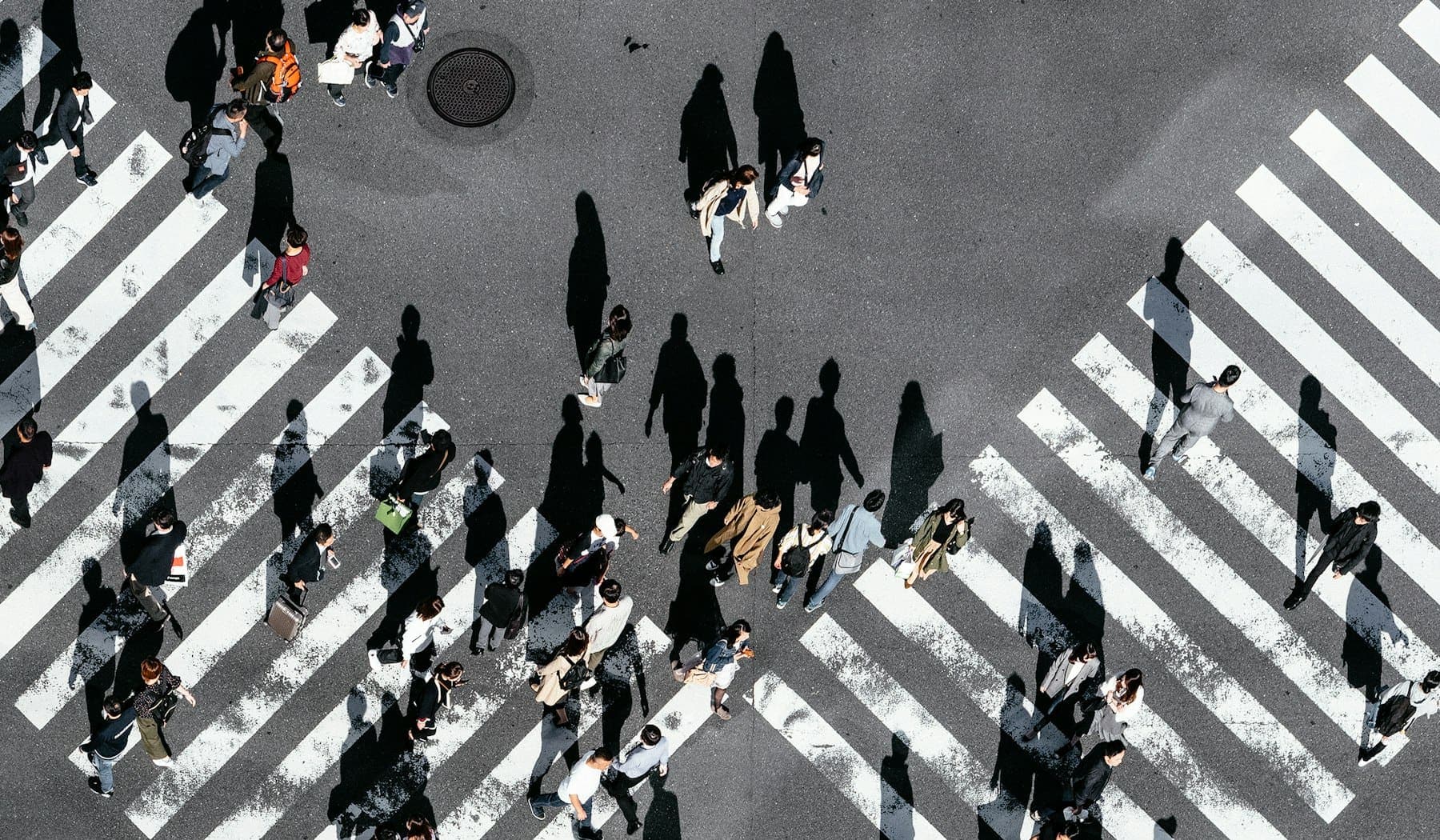 Shibuya Crossing seen from directly overhead as pedestrians cross in every direction
